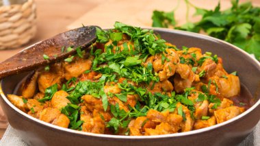 Tahta kahverengi bir masada, bir kasede doğranmış maydanoz serpiştirilmiş tavuk, yakın çekim.