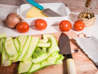 Kabak dilimlenmiş tabaklar sebze, peynir ve ahşap mutfak tahtasındaki bıçakla pişmiş rulo ekmek pişirmek için.