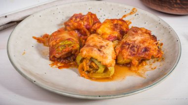 Mutfak masasında peynirle pişirilmiş sebzeli kabak dürümleri.