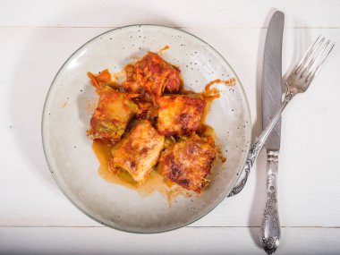 Mutfak masasında peynirle pişirilmiş sebzeli kabak dürümleri.