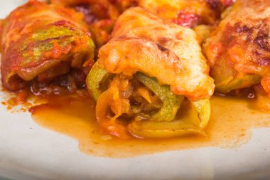 Mutfak masasındaki tabakta peynirle pişirilmiş sebzeli kabak dürümleri.