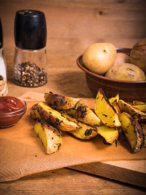 Ahşap bir tahta üzerinde Rustik fırında patates ve sos ve köhne ahşap bir masada baharatlar, yakın plan.