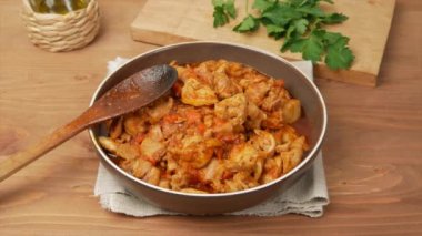 Tahta masadaki körili tavuk, bir kadın maydanozla bir tabak süslüyor.