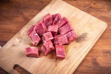 Tahta mutfak kesme tahtasındaki gulaş için taze çiğ et dilimleri.