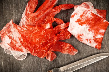 Kırmızı boya ya da kanla boyanmış eldivenler, bir bıçak ve üzerinde kan lekeleri olan bir peçete.