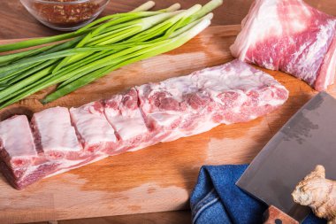 Bir parça çiğ domuz göbeği, pirzola ve yemek pişirmek için gerekli malzemeler.