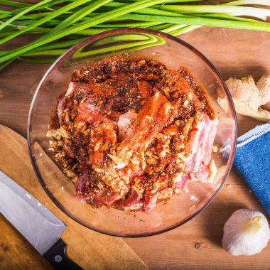 Baharatlı terbiye soslu cam kasedeki çiğ domuz eti parçaları. Yemek pişirmek için malzemeler, yakın çekim, üst manzara.