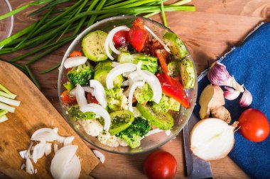 Cam bir kasedeki çiğ renkli sebzeler masada yemek pişirmek için baharat ve malzemeler, yakın plan, üst görüş.