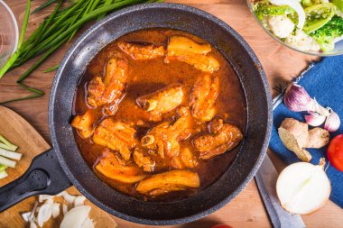 Baharatlı soslu pirzola ve büyük bir tavada Meksika ve Karayip mutfağı.