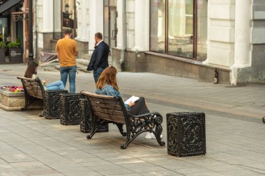 Moskova, Rusya, 27 Temmuz 2020 - sıradan şehir hayatı, genç kadınlar banklarda oturur ve üzerinde notlar ve bir akıllı telefon bulunan bir defterin içine bakarlar.