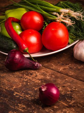 Kırsal bir ahşap masada taze taze sebzeler toplanmış. Yakın plan.