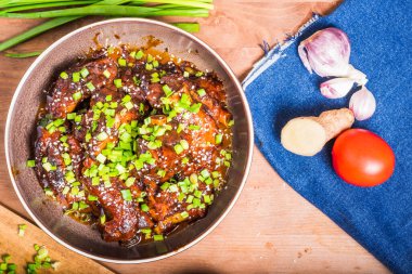 Baharatlı sosta pişirilmiş domuz pirzolası ve domuz pirzolası tabakta ve yakınlardaki kot peçetesinde malzemeler.