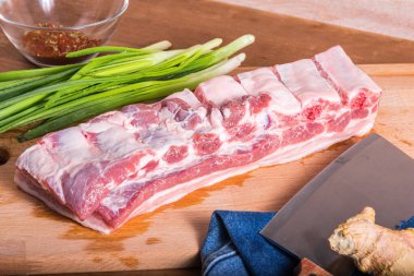 Çin yemeği malzemeleri. Kaburgalı bir parça domuz eti, yeşil soğan kasede Sichuan biberi ve kesme tahtasında zencefil.