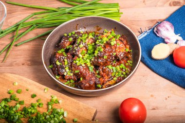 Baharatlı sosta kızarmış domuz eti, göğüs eti ve pirzola. Masanın üzerinde Asya yemeklerini hazırlamak için malzemelerle birlikte yeşil soğan serpiştirilmiş..