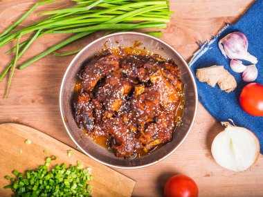 Yemek pişirmek için malzemelerle dolu bir tabakta tatlı ve ekşi sosta pişirilmiş domuz pirzolası, üst manzara. Baharatlı domuz yahnisi..