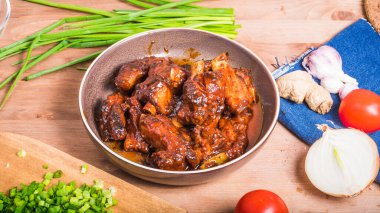 Kırmızı acı sosta pişmiş kaburgalar Çin usulü bir tabakta yemek pişirmek için malzemelerle birlikte.