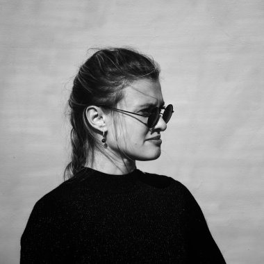 Siyah gözlüklü çekici bir genç kadın portresi ve siyah kazak, sert stil, siyah beyaz fotoğraf.