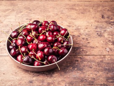 Olgun kirazlarla dolu bir kase ahşap bir masada, üst görünüm, boşluğu kopyala