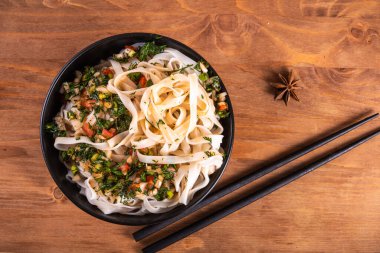 Baharatlı baharatlı soslu erişte, sarımsak ve biber ve soya sosu yemek çubuklarıyla dolu bir kasede, yakın plan, üst manzara.