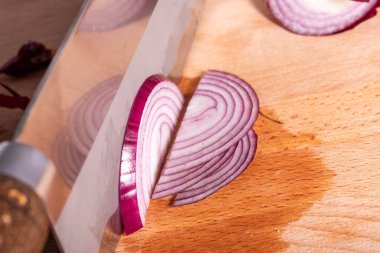 Kırmızı soğanı yarım halkalara dilimliyorum. Yakın plan.