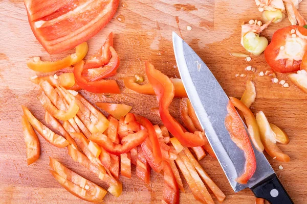 Sebze sosu pişirmek. Kesme tahtasında dilimlenmiş dolmalık biber. Bıçakla.