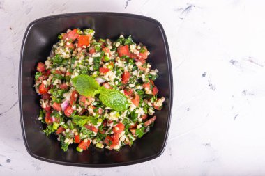 Tabouleh - Bulgurlu, domatesli ve otlu yaz Arap vejetaryen salatası açık arkaplanda, fotokopi alanı, üst manzara.