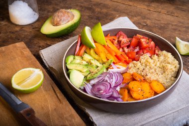 Modern Amerikan sağlıklı yiyecekler - kinoalı salata, avokado ve sebzeler masanın üstünde keten peçetede, yakın plan, kırsal tarzda.