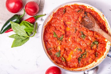 Makarna ve pizza için acı sos masada malzemelerle dolu bir tavada - domates, fesleğen ve acı biber, üst manzara, kopyalama alanı