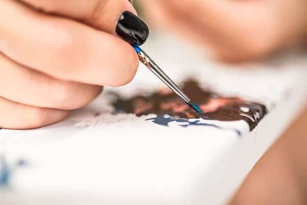 Woman paints a picture by numbers, close-up, hands with a brush