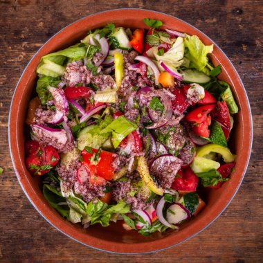 Vejetaryen Akdeniz salatası marul, domates, salatalık ve zeytinyağlı soğan ve sümac soslu bir kase, üst manzara.
