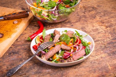 Sebzeli ve biftekli nefis salata, masada servis edilen bir tabak dolusu salata.