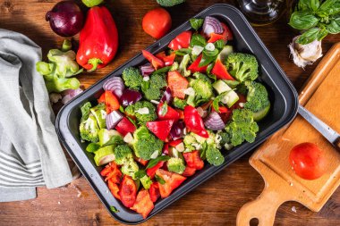 Dilimlenmiş sebzeler, brokoliler, domatesler, biberler ve kabaklar mutfak masasında malzemelerle dolu bir kabak örtüsü, üst manzara - vejetaryen sağlıklı mutfak