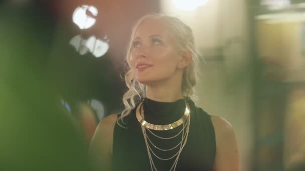 Cute blond with gold ornaments stands in a flower gallery — Stock Footage Cute blond with gold ornaments stands in a flower gallery Royalty Free Stock Video