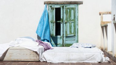 Beyaz duvar zeminli rahat bir çatı ve eski yeşil hasarlı pencerenin önünde iki kibrit..