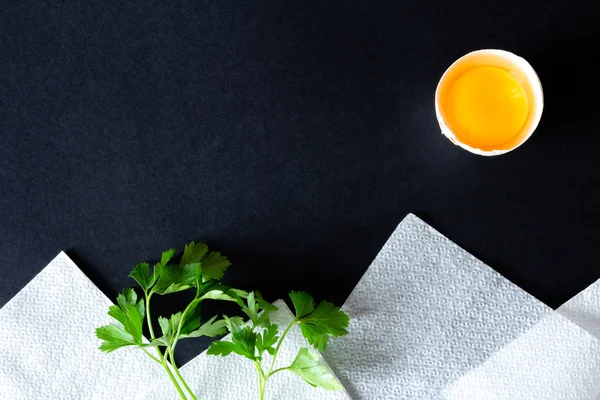 Kırık yumurta, maydanoz ve beyaz peçeteler oluşan manzara
