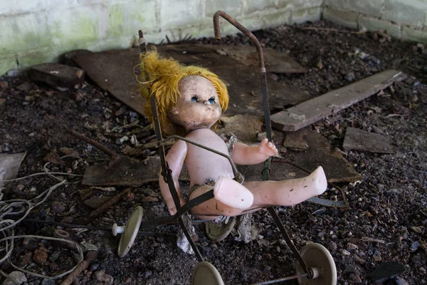 UCRÂNIA. Zona de Exclusão de Chernobil. - 2016.03.19. Velha boneca abandonada em um carrinho de brinquedo quebrado — Fotografia de Stock