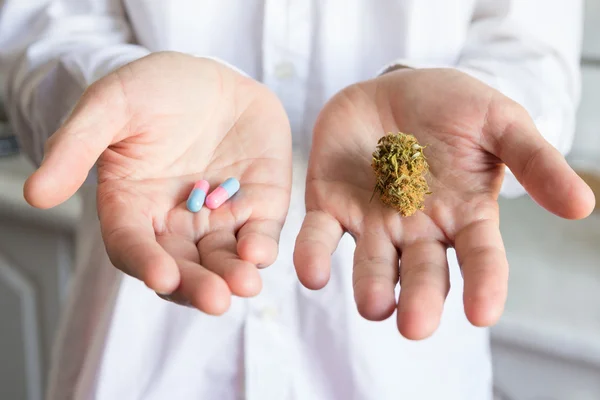 Docteur main tenant bourgeon de cannabis médical et des pilules — Photo
