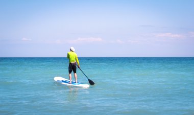 Paddle yardımıyla denizde yüzen sörf tahtası adam