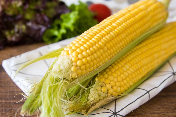 Kahverengi ahşap tahta üzerinde olgun sarı mısır koçan