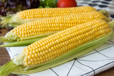 Kahverengi ahşap tahta üzerinde olgun sarı mısır koçan