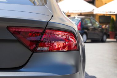 Park halindeki gri grafit otomobilin arka lambası ve bulanık arka plan