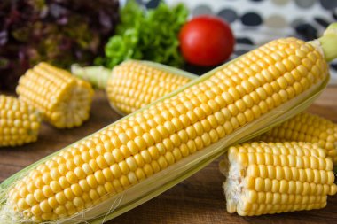 Kahverengi ahşap tahta üzerinde olgun sarı mısır koçan