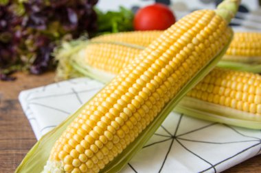 Kahverengi ahşap tahta üzerinde olgun sarı mısır koçan