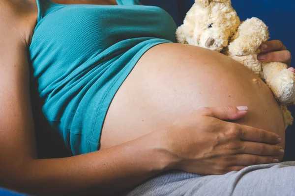 Фото беременной женщины с плюшевым мишкой на нем — стоковое фото