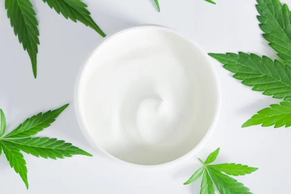 绿色大麻叶 白色背衬上有一罐大麻脂乳液 Skincare Beauty Spa Concept 免版税图库图片