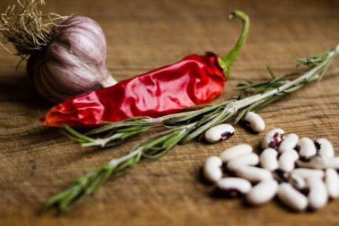 Şili biber, biberiye ve chesnokm kahverengi kesme tahtası üzerinde