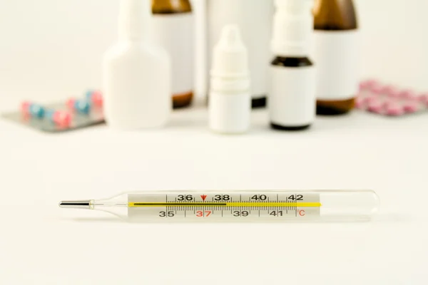 Termometer och droger på vit bakgrund — Stockfoto