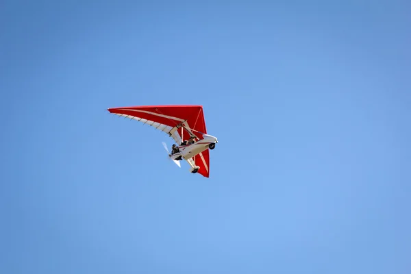 Gemotoriseerde hangen-zweefvliegtuig stijgende in de blauwe hemel — Stockfoto