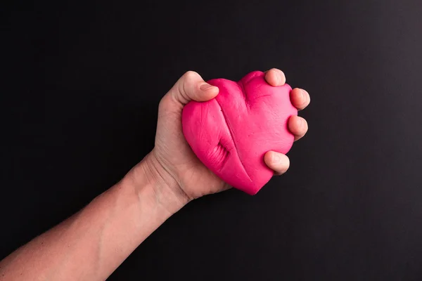 Mens siyah bir zemin üzerine sıkma pembe kalp el