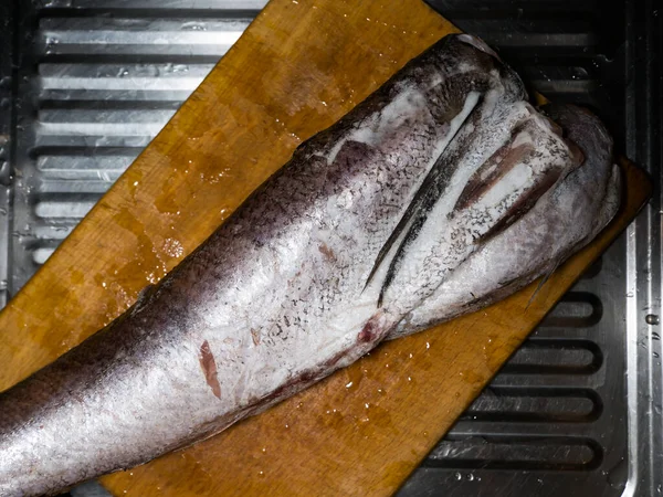 Pescado de merluza grande congelado se encuentra en el tablero de la cocina —  Fotos de Stock
